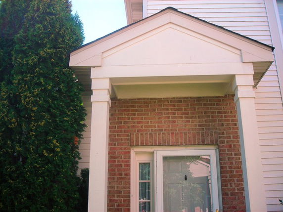 Front view of a house entrance with brick and white siding.