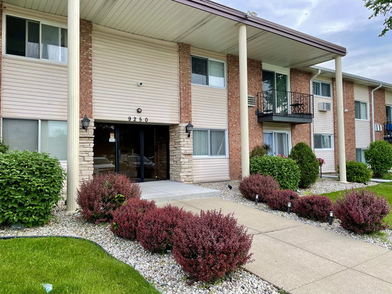 Front view of a two-story apartment building with balconies and entrance.