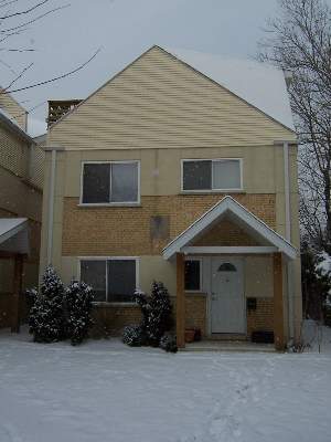 Front view of a two-story house with a triangular roof and snow-covered entrance.
