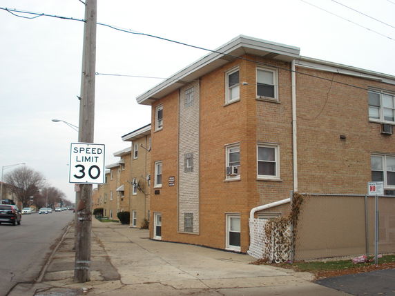 Front view of a three-story brick apartment building with corner windows.