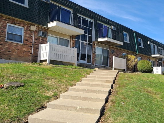 Front view of a two-story residential building with balconies and brick facade.