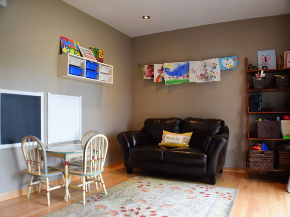 Room with a small table and chairs, couch and children's art on the walls.