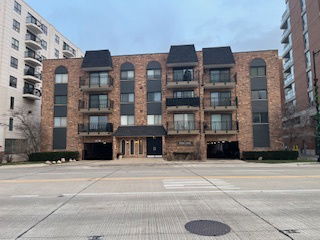 Front view of a multi-story brick building with balconies and a central entrance.