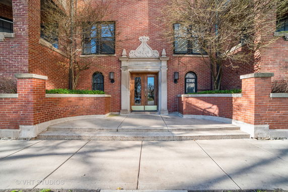 Front entrance of a brick building with decorative stone trim and double doors.
