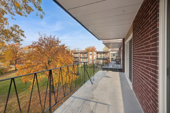 Balcony view overlooking autumn trees and nearby building.