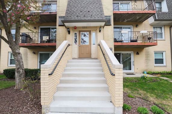 Front view of a multi-story building with balconies and entrance staircase.