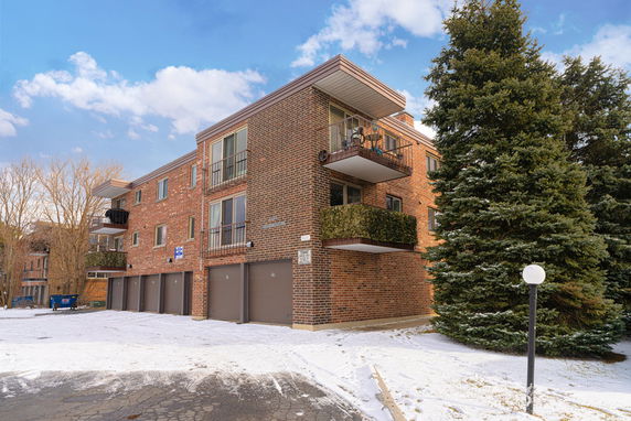 Front view of a three-story brick apartment building with balconies.