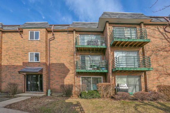 Front view of a multi-story brick apartment building with balconies.
