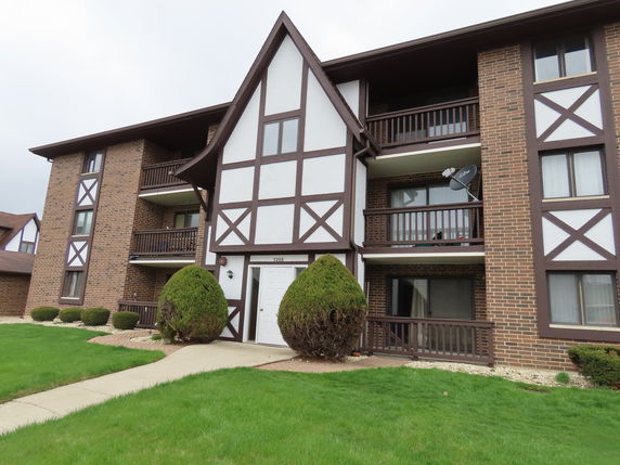 Front view of a multi-story apartment building with brick and timber facade.