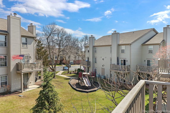 View of an apartment complex with balconies and a children's playground in the courtyard.
