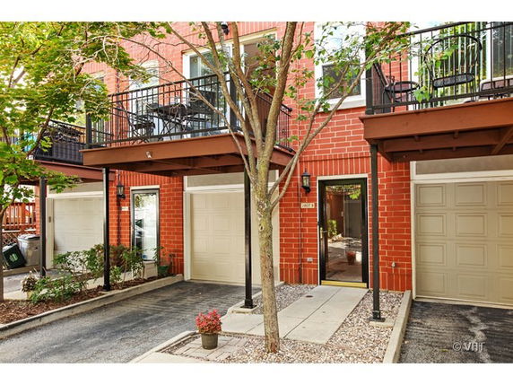 Front view of a multi-story brick townhouse with garages and balconies.