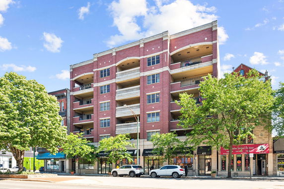 Front view of a multi-story building with retail shops on the ground floor.