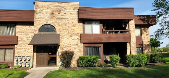 Front view of a two-story building with brick facade and brown wooden accents.