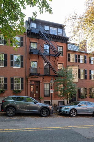 Front view of a multi-story brick building with fire escape stairs.