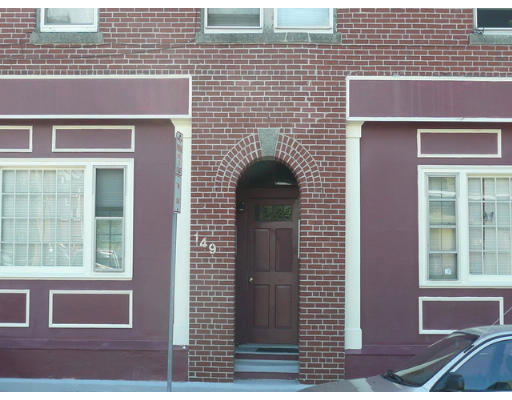 Front view of a brick building with an arched wooden door and two windows.