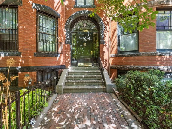 Front view of a brick building entrance with stairs leading up to a green door.