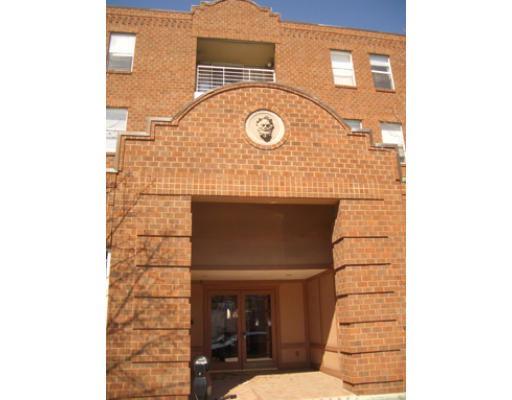 Front view of a brick multi-story building entrance with architectural detailing.