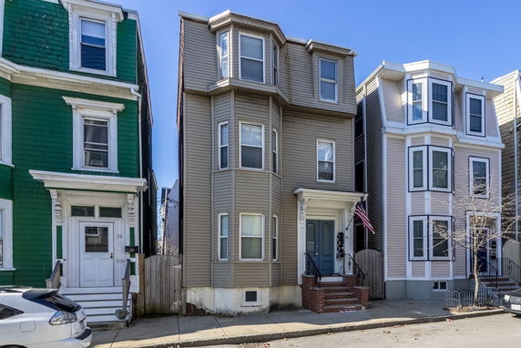 Front view of a row of three-story townhouses with distinct facades and bay windows.