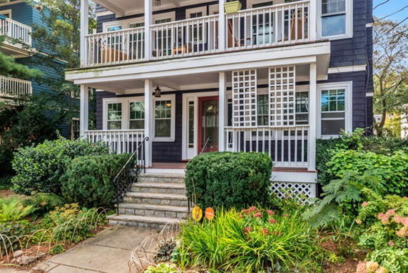 Front view of a house with two-story porches and steps leading up to the entrance.