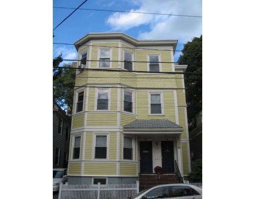 Front view of a yellow multi-story house with white trim and two entrances.