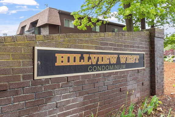 Front view of a brick wall with a sign reading 'Hillview West Condominium'.