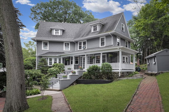 Front view of a two-story house with a wraparound porch and gabled roof.