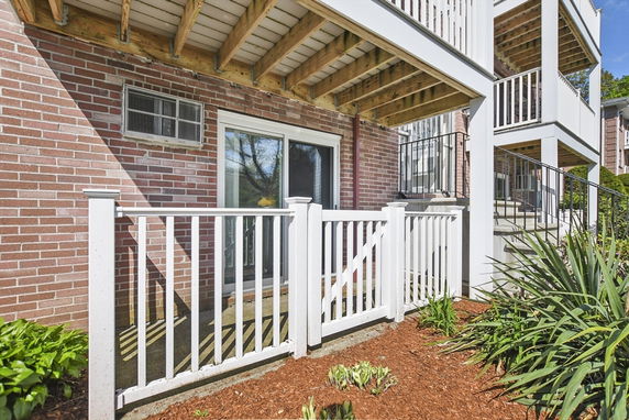 View of a house with a sliding glass door and wooden balcony above.