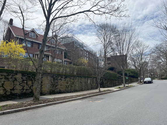 Street view of a two-story brick house with dormer windows and a sloped roof.