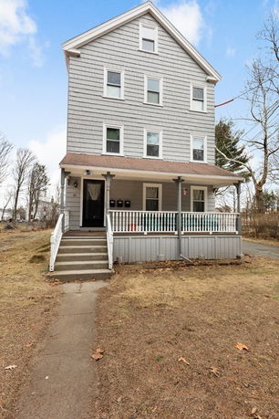 Front view of a three-story house with a porch and multiple windows.
