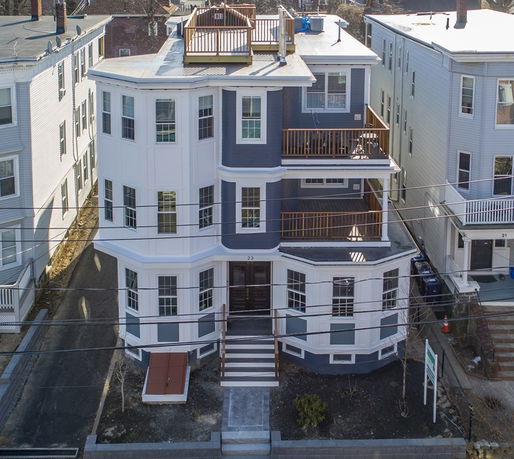 Front view of a multi-story residential building with balconies and rooftop terrace.
