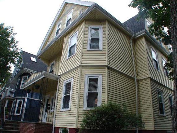 Front view of a multi-story house with yellow siding and a covered entrance.