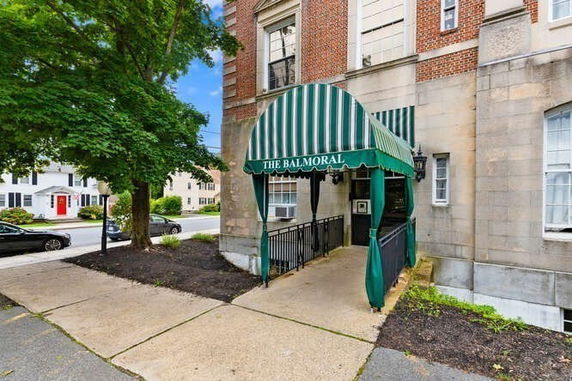 Entrance of a brick building with a green striped canopy labeled 'The Balmoral'.