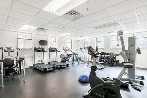Interior view of a gym with exercise equipment including treadmills and stationary bikes.