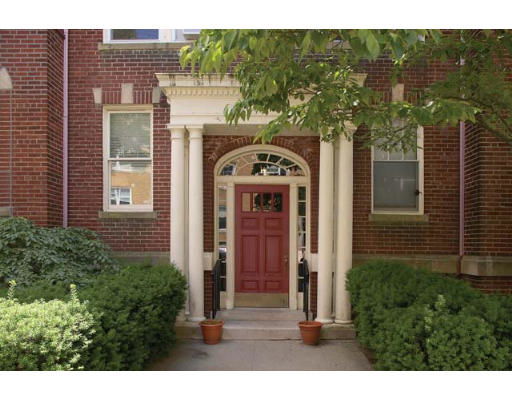 Front view of a building entrance with a red door and decorative columns.