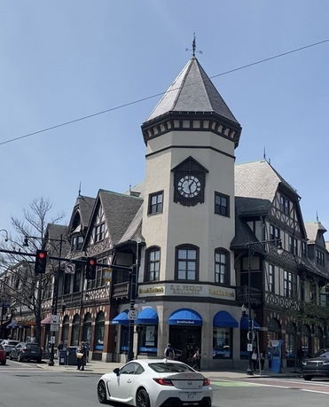 Front view of a building with a distinctive clock tower and Tudor-style architecture.