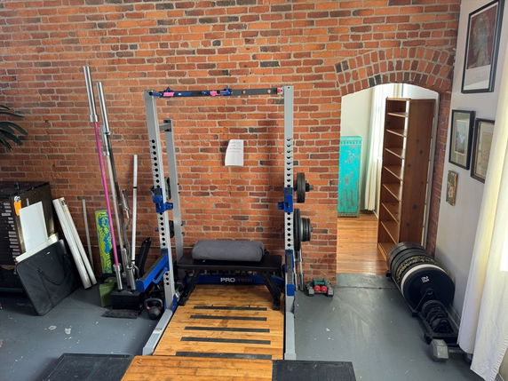Indoor gym area with weightlifting equipment and brick walls.