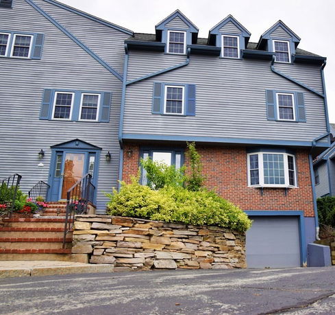 Front view of a multi-story house with blue siding and a brick facade.