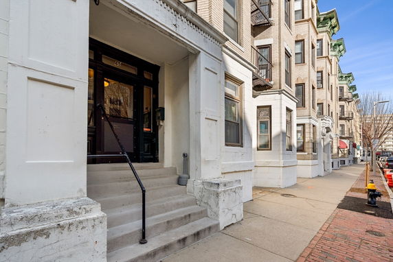 Front view of a multi-story residential building with an entrance and steps.