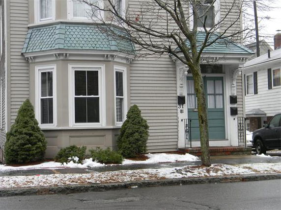 Front view of a two-story house with bay windows and a green door.