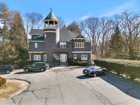 Front view of a house with a turret and multiple gables.