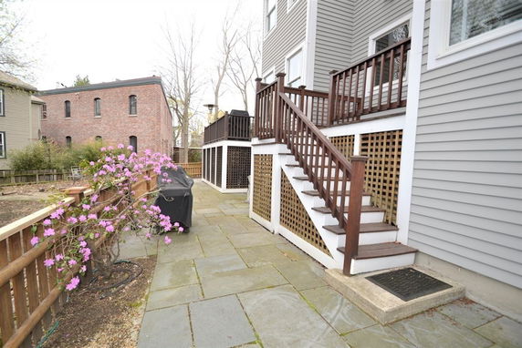 View of the back of a house with a staircase leading to an elevated patio.
