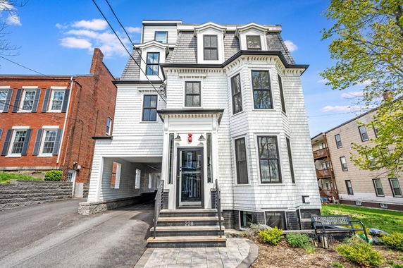 Front view of a multi-story house with white siding and dormer windows.