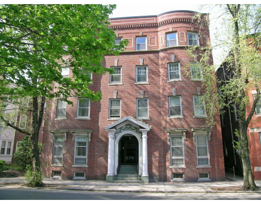 Front view of a three-story brick building with symmetrical windows and an arched entrance.