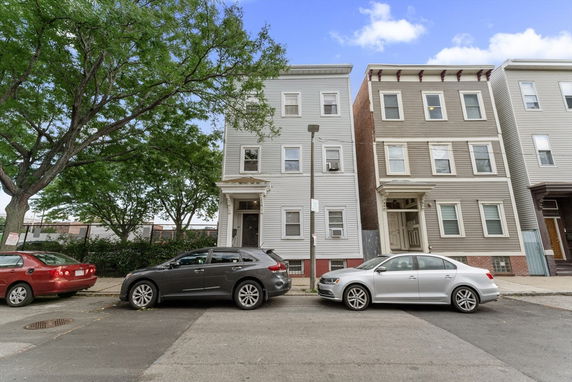 Front view of adjacent multi-story houses with parking in front.