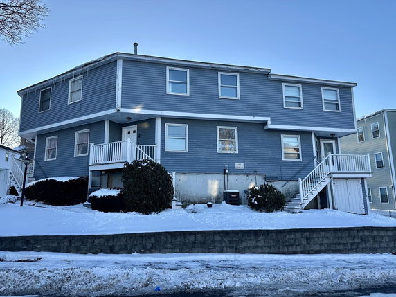 Front view of a two-story blue house with multiple entrances and steps leading to the doors.