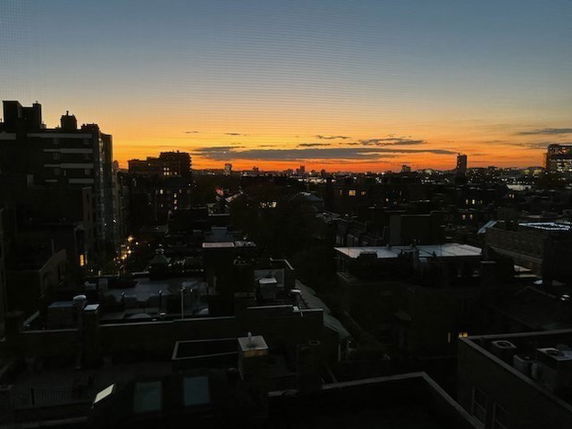 Wide-angle view of a cityscape during sunset with buildings silhouetted against the sky.