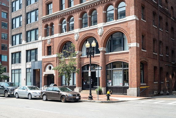 Front view of a multi-story brick building with arched windows and decorative details.