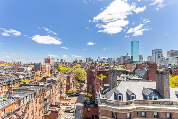 Panoramic view of a cityscape with various buildings and a bright blue sky.