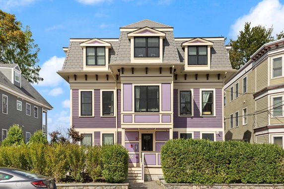 Front view of a three-story residential house with a distinctive roof design and purple exterior.