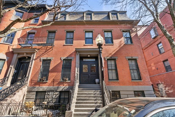 Front view of a multi-story brick house with steps leading to the entrance.